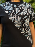 Person wearing a black t-shirt with floral and butterfly design outdoors