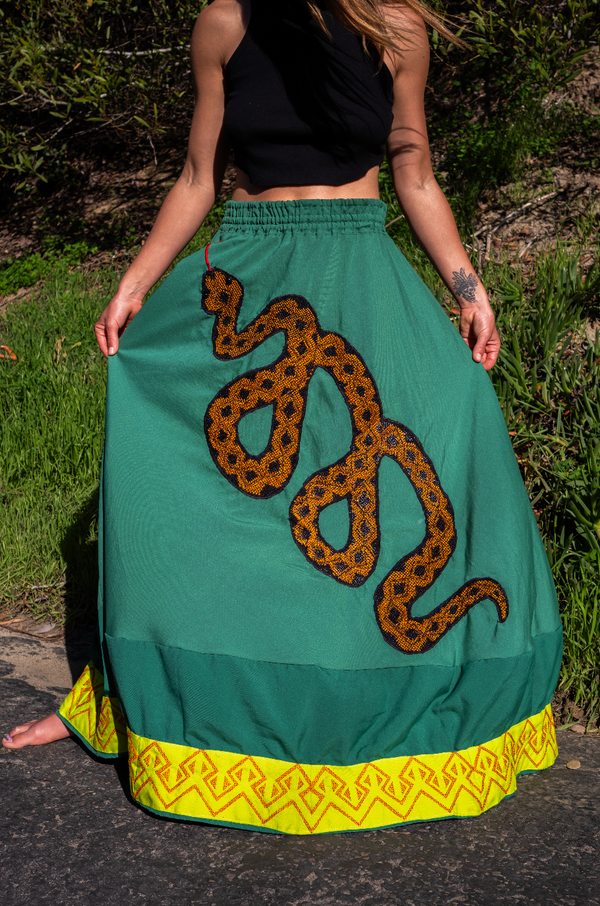 Green ceremonial skirt with bold serpent embroidery and yellow geometric borders, handcrafted by Amazonian artisans using ancestral techniques for ritual expression.