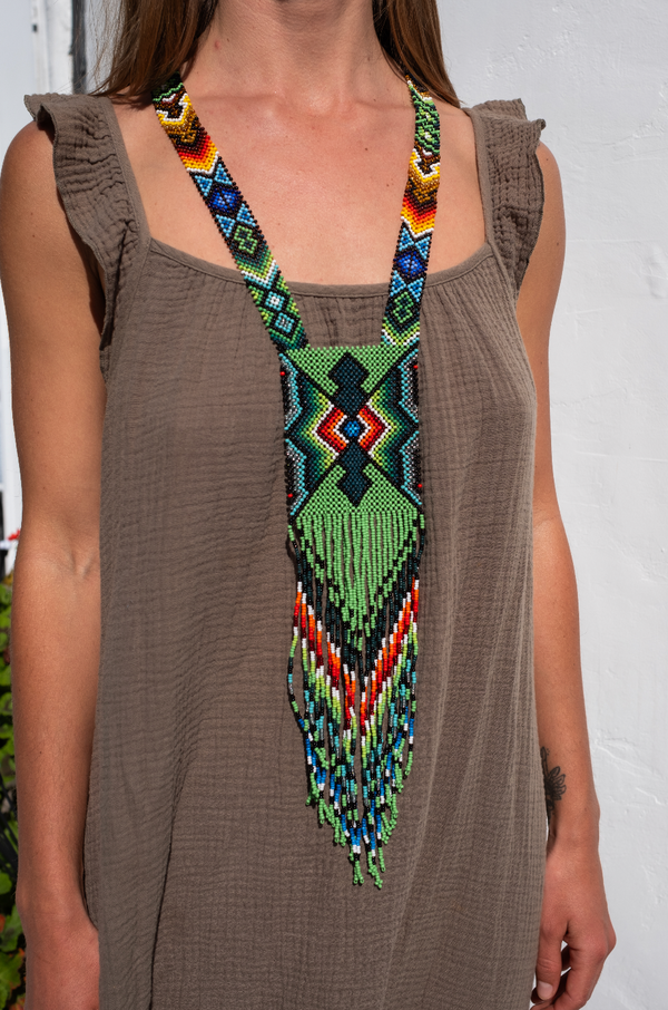 Handwoven sacred geometry necklace with green diamond-shaped beadwork and fringe, crafted by indigenous South American artisans using traditional techniques.