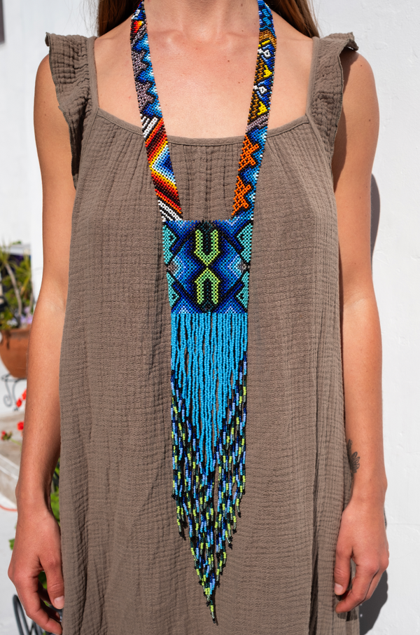 Handmade Ocean Sky beaded necklace with sacred geometric pattern and cascading fringe, crafted by South American tribal artisans in vivid blue, green, and orange.